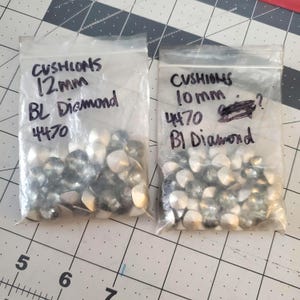 Pu&ograve; includere: Due sacchetti di strass trasparenti, un sacchetto etichettato "CUSHIONS 10mm 4470 BI Diamond" e l'altro etichettato "CUSHIONS 12mm BL Diamond 4470".