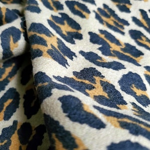 May include: Close-up of a beige fabric with a brown and black leopard print pattern.