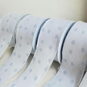 May include: Four spools of white ribbon with light blue polka dots.