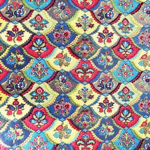 May include: A close-up of a fabric with a repeating pattern of colourful floral medallions. The design features red, blue, yellow, and green hues, creating a vibrant and intricate textile design. The pattern is reminiscent of vintage or bohemian styles.