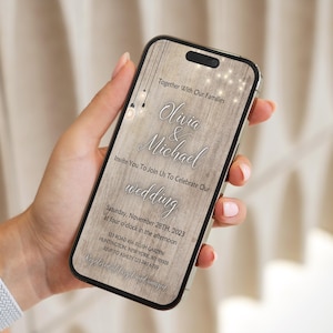 May include: A smartphone displays a wedding invitation with the names "Olivia & Michael" in elegant script. The invitation includes the date, time, and location, set against a wood-grain background with decorative lights.