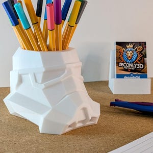 Peut inclure: Porte-stylos blanc imprimé en 3D en forme de casque de Stormtrooper de Star Wars. Le porte-stylos est rempli de marqueurs colorés.