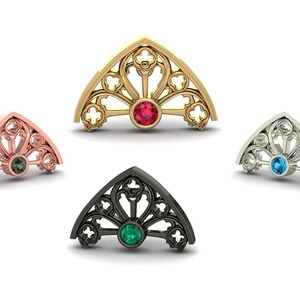 Può includere: Quattro gioielli ad arco ornati in oro, oro rosa, argento e nero. Ognuno presenta una gemma centrale: rossa, verde, blu e smeraldo. I disegni assomigliano a vetrate, con motivi intricati e una disposizione simmetrica.