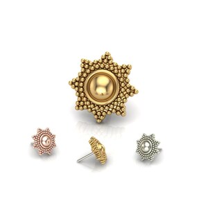 May include: A collection of four nose studs in various metallic finishes. The largest stud is gold, star-shaped, and has a central sphere surrounded by small, beaded details. The other three studs are smaller, with a similar design in rose gold, gold, and silver.