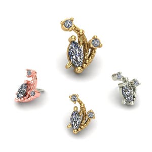 May include: Four pieces of jewelry, each featuring a marquise-cut gemstone and smaller round gemstones. The jewelry is in gold, rose gold, and silver tones. The pieces have a floral or abstract design.