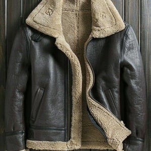 Può includere: Una giacca di pelle marrone con fodera in montone. La giacca ha una chiusura a zip e un colletto alto.