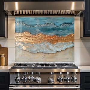 May include: A kitchen backsplash featuring an abstract ocean scene with blue, gold, and beige tones. The artwork is mounted above a stainless steel range with a black cabinet and white countertop.