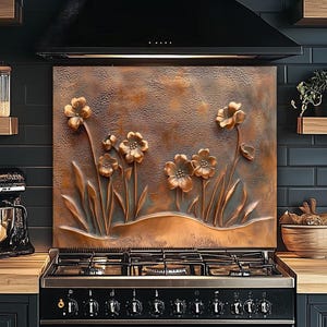 Pode incluir: Um painel de cozinha cor de cobre com um design floral em relevo. As flores e caules são levantados da superfície, criando um efeito tridimensional. O painel é instalado acima de um fogão a gás preto.