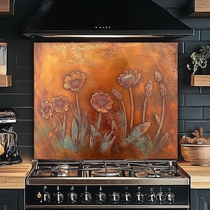 May include: A copper-colored kitchen backsplash featuring embossed floral designs. The artwork depicts several flowers with detailed petals and stems, set against a textured background. The backsplash is installed above a black stove.
