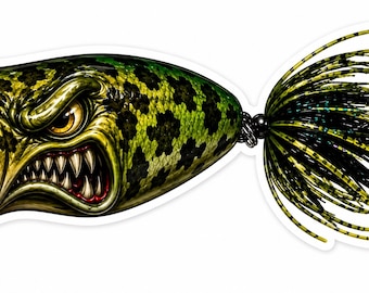 Puede incluir: Ilustración detallada de un señuelo de pesca con un diseño de cara de pez agresivo. El señuelo presenta una boca roja, dientes afilados y un ojo amarillo. El cuerpo es verde con manchas negras, y la cola tiene hebras negras y amarillas.