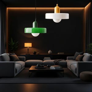 May include: A dark living room with a gray sectional sofa, a black coffee table, and two pendant lights. One light has a green shade and the other has a white shade.