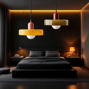 May include: Two modern pendant lights with yellow and red shades hang over a black bed with white bedding in a dark room.