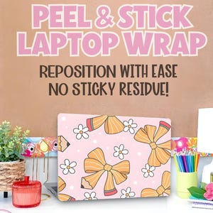 May include: A pink laptop wrap with a pattern of orange bows, pencils, and white flowers. The text on the wrap says "PEEL & STICK LAPTOP WRAP". The background is a light brown color with the text "REPOSITION WITH EASE NO STICKY RESIDUE!"