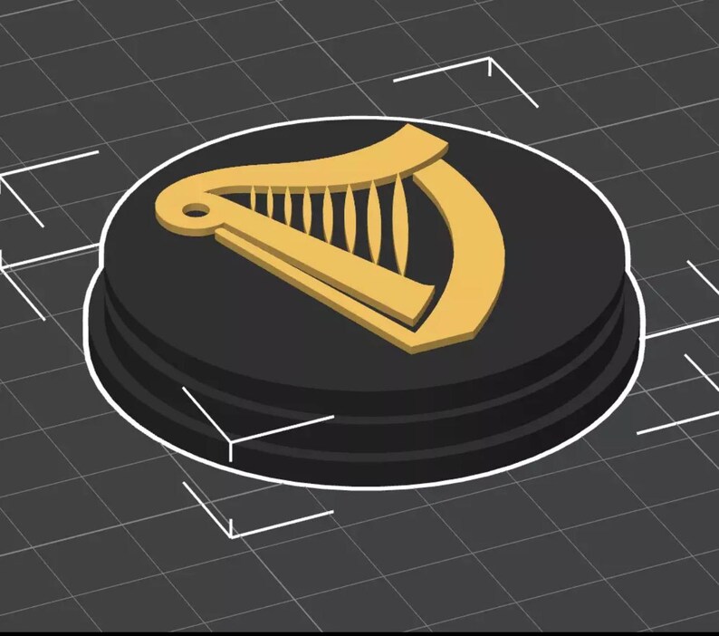 Op de afbeelding: Een zwart en goud rond embleem met een gouden harp ontwerp. Het embleem is verhoogd op een zwarte cirkelvormige basis met een witte rand. De achtergrond is een donkergrijze raster.