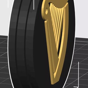 Op de afbeelding: Een zwart en goud rond embleem met een gouden harp op een zwarte achtergrond. Het embleem heeft een driedimensionale uitstraling en is waarschijnlijk een logo of designelement. Het ontwerp is eenvoudig en gedurfd, met een duidelijk contrast tussen de kleuren.