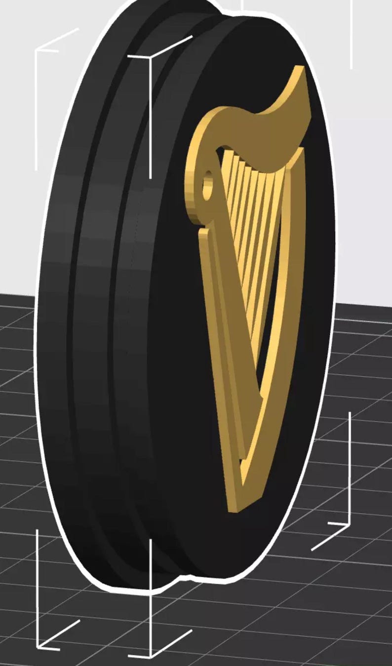 Op de afbeelding: Een zwart en goud rond embleem met een gouden harp op een zwarte achtergrond. Het embleem heeft een driedimensionale uitstraling en is waarschijnlijk een logo of designelement. Het ontwerp is eenvoudig en gedurfd, met een duidelijk contrast tussen de kleuren.