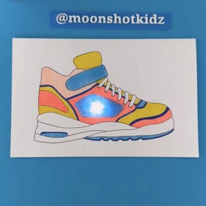 Op de afbeelding: Een handgetekend ontwerp van een kleurrijke sneaker met een lichtblauw gloeiend detail. De tekening is op wit papier en de tekst "@moonshotkidz" is in wit op een blauwe achtergrond geschreven.