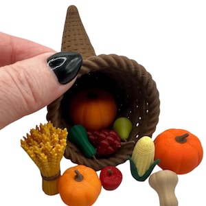 May include: A miniature cornucopia overflowing with autumn harvest items. The brown woven basket holds an orange pumpkin, red berries, green zucchini, and a yellow pear. Additional pumpkins, corn, and wheat are scattered around.