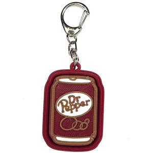 May include: Red and brown 3D printed keychain shaped like a Dr Pepper can. The keychain has a silver metal ring.