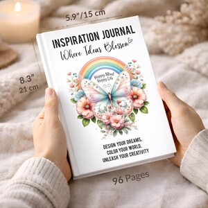 May include: A white hardcover journal titled INSPIRATION JOURNAL Where Ideas Blossom, featuring a butterfly, rainbow, and flowers. Text reads Happy Mind Happy Life and DESIGN YOUR DREAMS, COLOR YOUR WORLD, UNLEASH YOUR CREATIVITY. Dimensions are 5.9" by 8.3".