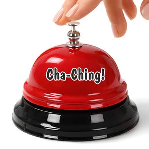 May include: A red desk bell with a black base and a silver top. The bell features the words "Cha-Ching!". A hand is pressing the bell's top. The bell is likely made of metal.