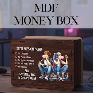 Op de afbeelding: Houten MDF-geldkist met de tekst "MDF MONEY BOX". De doos heeft een afbeelding van twee tieners die kauwgom blazen. Tekst op de doos luidt "TEEN MISSION FUND" en "Shh! Something BIG is Growing Here!"