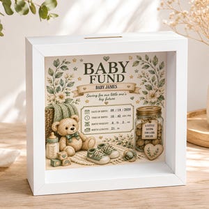 Könnte beinhalten: Ein weißer, quadratischer Schattenfugenrahmen mit einem personalisierten Baby Fund Design. Das Innere zeigt einen Teddybären, Babyschuhe, ein Fläschchen und ein Glas mit der Aufschrift A Little Saving For A Big Dream. Der Text enthält Baby James, Geburtsdaten und florale Akzente.