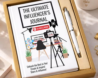 May include: A white hardcover journal titled The Ultimate Influencer's Journal with a graphic of a desk, camera, and lighting equipment, paired with a white ballpoint pen in a gold gift box. The cover text reads Unleash the Best in You!