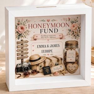 Może przedstawiać: Biała, kwadratowa skarbonka w formie ramki z napisem HONEYMOON FUND, EMMA & JAMES oraz EUROPE. Projekt zawiera ilustracje słomkowego kapelusza, aparatu fotograficznego w stylu vintage, walizki, paszportu, muszli oraz szklanego słoika z etykietą.
