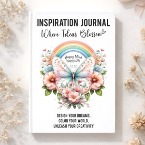 May include: A white journal titled INSPIRATION JOURNAL Where Ideas Blossom. The cover features a central butterfly, a rainbow, and pink and blue flowers. Text reads Happy Mind Happy Life, DESIGN YOUR DREAMS, COLOR YOUR WORLD, UNLEASH YOUR CREATIVITY.