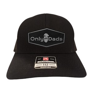 May include: Black trucker hat with a mesh back and a curved brim. The front features a gray patch with the text "Only Dads" and a stylized beard graphic. The hat is adjustable and has a Richardson label.