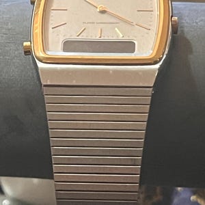 May include: A Seiko Quartz analog-digital watch with a silver-tone rectangular case, a gold-tone bezel, and a silver-tone metal link bracelet. The watch face features gold-tone hour markers, gold-tone hands, and a digital display window at the bottom.