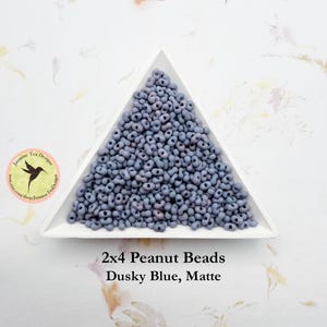 May include: A triangular tray filled with 2x4 Dusky Blue Matte Peanut Beads. The beads are a light blue color with a matte finish.