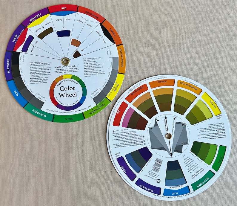 May include: Two color wheels, one with a traditional color wheel layout and the other with a more modern layout. Both wheels feature a variety of colors, including red, orange, yellow, green, blue, and violet. The text on the wheels reads "A guide to mixing color Color Wheel".