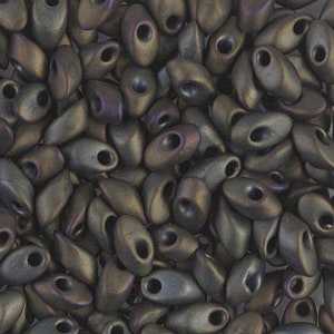 May include: A close-up of a pile of dark brown and iridescent seed beads. The beads are oval shaped with a small hole in the center.