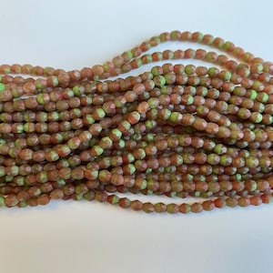 May include: Strands of faceted beads in shades of brown and green. The beads have a geometric shape and are strung together, creating a textured and colorful display. Ideal for jewelry making or craft projects.
