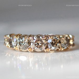 Puede incluir: Un anillo de banda de oro con seis diamantes redondos y transparentes engastados en pavé.