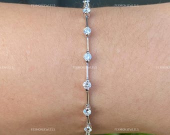 May include: A delicate silver bracelet featuring five round, clear gemstones. The gemstones are connected by thin silver bars. The bracelet is shown on a person's wrist. The text "FEXMONJEWELS" is visible in the background.