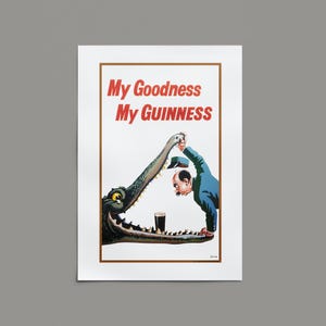 Op de afbeelding: Vintage Guinness-advertentie met een cartoonillustratie. Een man in een blauw pak wordt bedreigd door een krokodil, met een pint Guinness in zijn kaken. De tekst "My Goodness My Guinness" staat bovenaan.