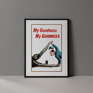 May include: Framed vintage advertisement poster with the text "My Goodness My Guinness" in red. The image depicts a man in a blue suit and a crocodile with a pint of Guinness. The crocodile is holding the man's hat.