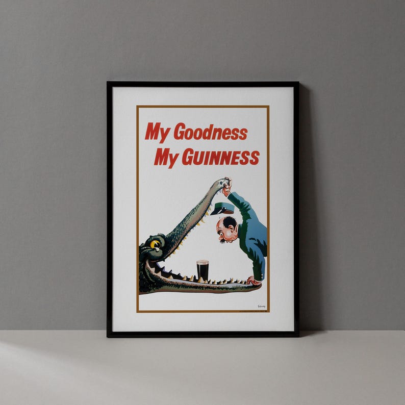 May include: Framed vintage advertisement poster with the text "My Goodness My Guinness" in red. The image depicts a man in a blue suit and a crocodile with a pint of Guinness. The crocodile is holding the man's hat.