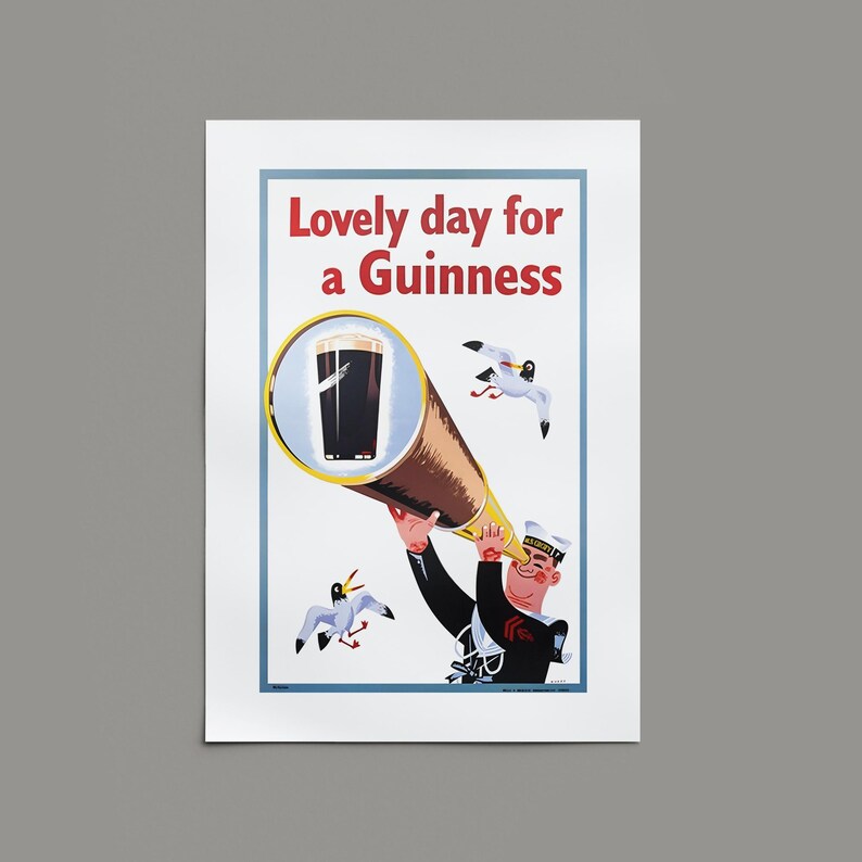 Op de afbeelding: Vintage poster met een zeeman die door een telescoop naar een pint Guinness kijkt. De poster heeft de tekst "Lovely day for a Guinness" in het rood. Twee zeemeeuwen vliegen op de achtergrond.