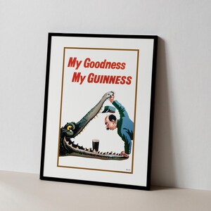 May include: Framed vintage advertisement poster with the text "My Goodness My Guinness" in red. The illustration depicts a man and a crocodile with a pint of Guinness. The poster is in a black frame.