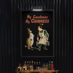 K&ouml;nnte beinhalten: Gerahmtes Vintage-Guinness-Poster mit einem K&auml;nguru und einem Mann, der Eimer tr&auml;gt. Der Text "My Goodness My Guinness" ist orange. Das Kunstwerk befindet sich vor einem schwarzen Hintergrund, ideal f&uuml;r eine Bar.