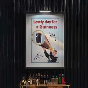 May include: A framed vintage advertisement for Guinness stout. The poster features a sailor looking through a telescope at a pint of Guinness, with the text "Lovely day for a Guinness" in red. Two seagulls are flying in the background.