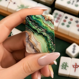 May include: A rectangular mahjong tile featuring a marbled design with swirling shades of emerald green, sage, and cream, accented by metallic gold veins and textured glitter details that mimic the appearance of natural agate stone.