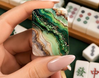 May include: A rectangular mahjong tile featuring a marbled design with swirling shades of emerald green, sage, and cream, accented by metallic gold veins and textured glitter details that mimic the appearance of natural agate stone.