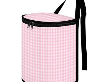 May include: A cylindrical cooler bag with a pink and white gingham pattern. The bag has a black zipper, trim, and adjustable shoulder strap. The bag is designed to keep items cold.