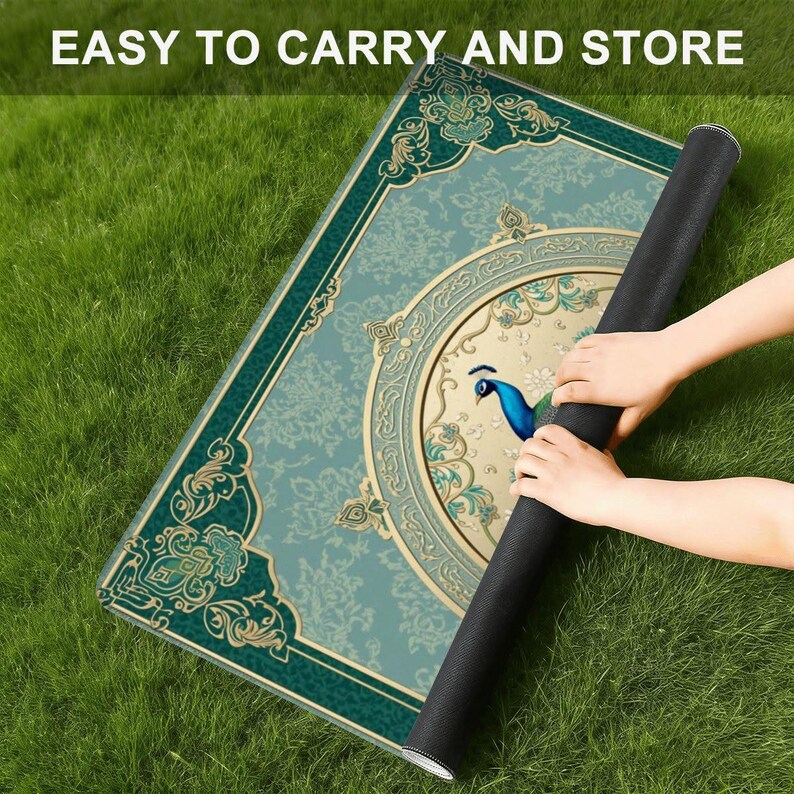 Puede incluir: Una alfombrilla rectangular con un patr&oacute;n de damasco ornamentado en verde azulado y dorado, con un medall&oacute;n circular central que contiene la ilustraci&oacute;n de un pavo real azul. La alfombrilla est&aacute; parcialmente enrollada, mostrando el reverso negro.