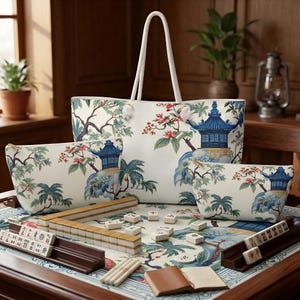 K&ouml;nnte beinhalten: Eine gro&szlig;e wei&szlig;e Tragetasche und zwei passende Rei&szlig;verschlusstaschen mit blauem Pagoden-, Palmen- und Blumenmuster. Ein Mahjong-Set mit elfenbeinfarbenen Spielsteinen, dunkelbraunen Haltern und einer passenden bedruckten Spielmatte.